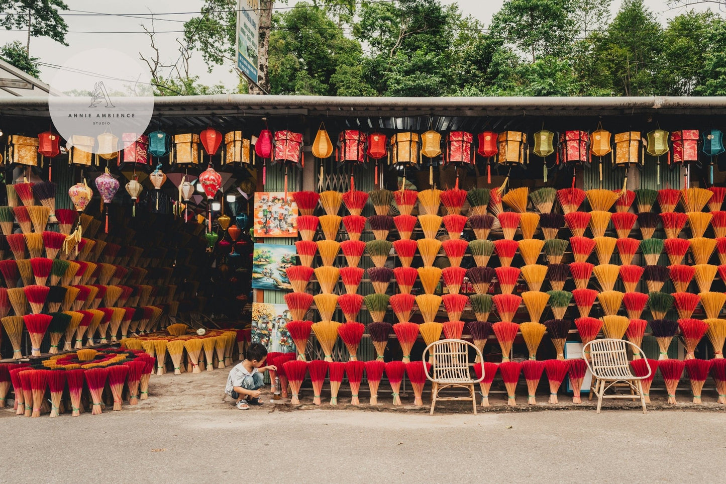 A vibrant display at the Incense Shop features colorful sticks and lanterns, with someone sitting nearby.