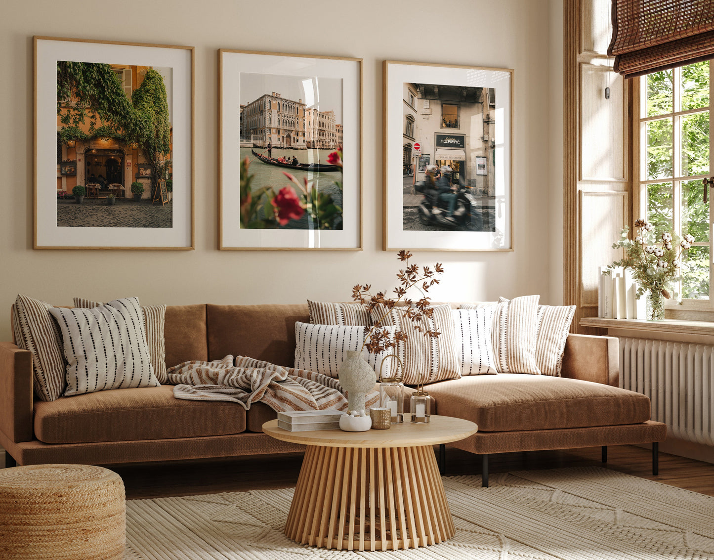 A cozy living room with a brown sofa, striped pillows, a round coffee table, and the Italy - Set of 3 wall art.
