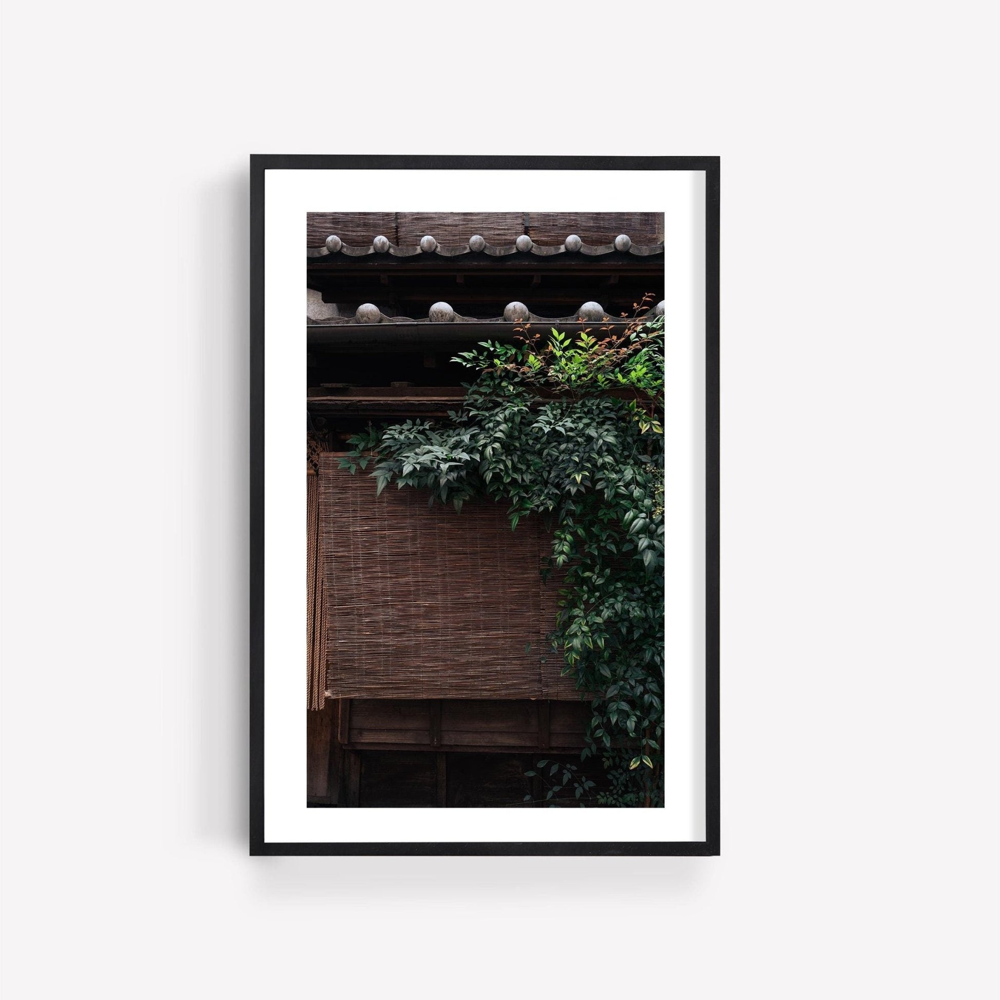 Framed photo titled Kagurazaka Essence featuring a traditional building with a tiled roof and climbing greenery against a plain wall.