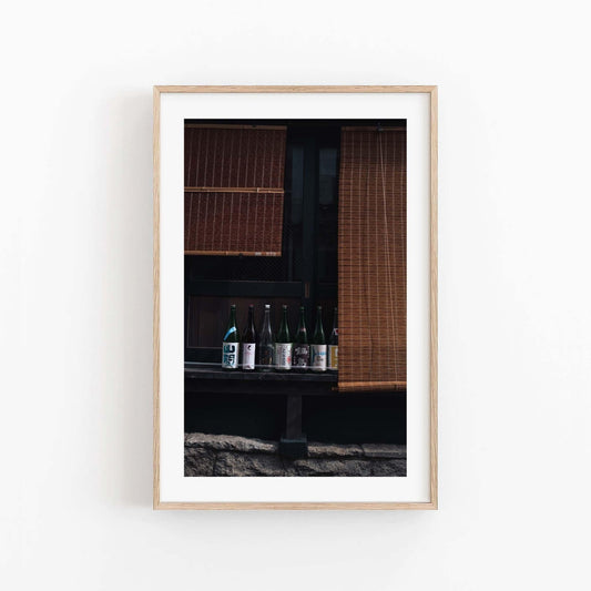 Framed photo of Kagurazaka Sake bottles on a window ledge with wooden blinds.