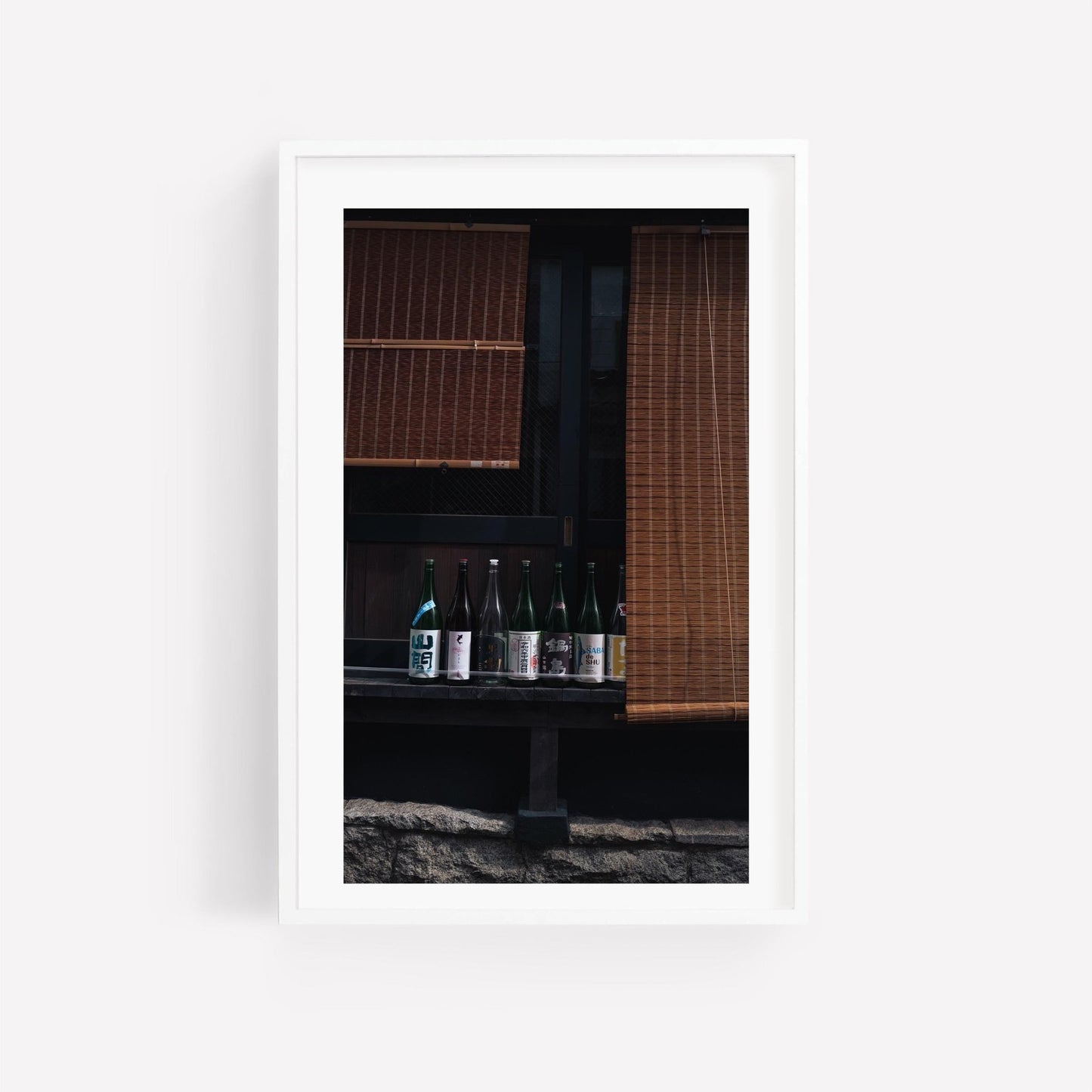 Framed photo of Kagurazaka Sake bottles on a shelf with bamboo blinds in the background.