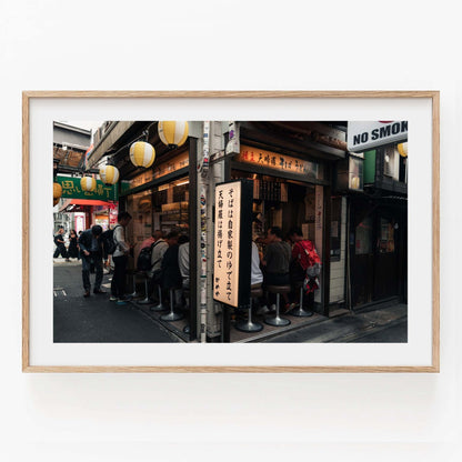 Framed photo of Kameya Soba, capturing the hustle of a street food stall with people seated and passing by.