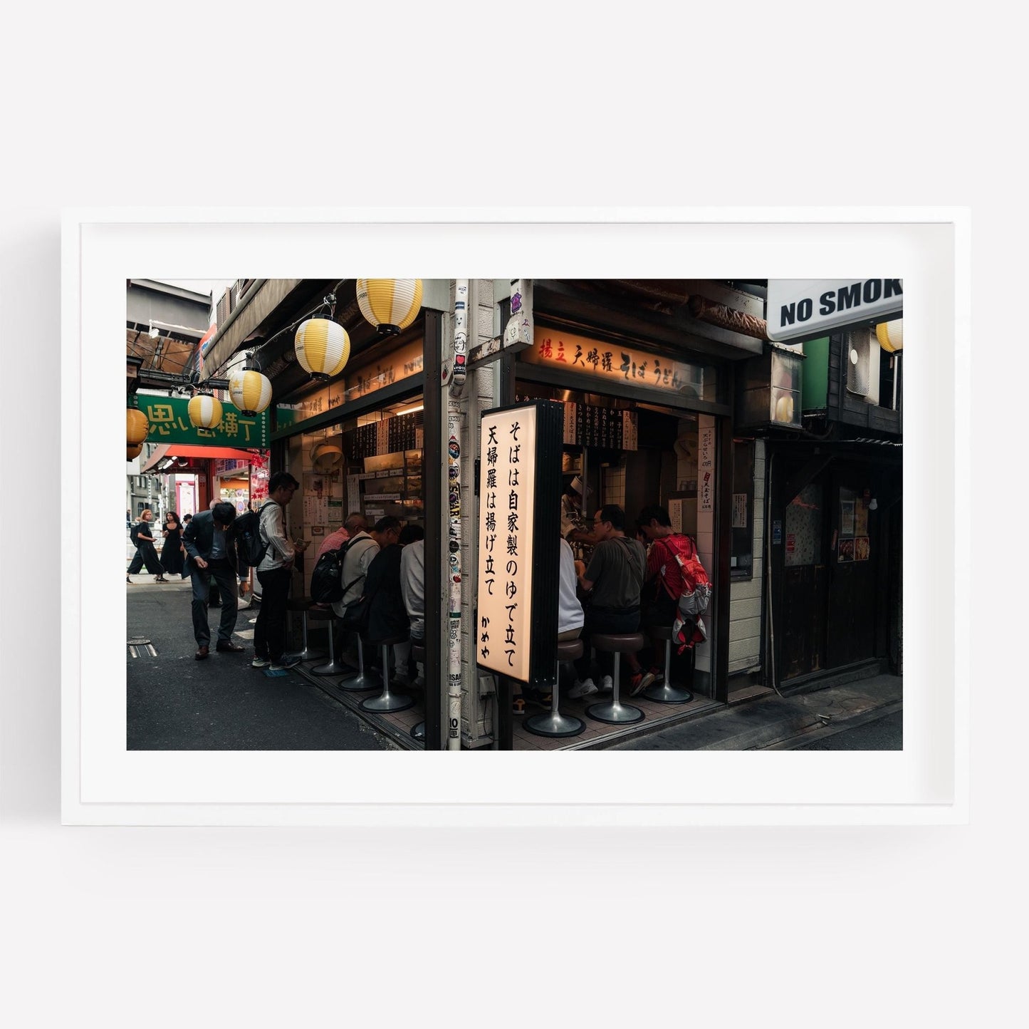 Kameya Soba, a small restaurant on a bustling street, features guests seated at a narrow counter amid hanging lanterns.