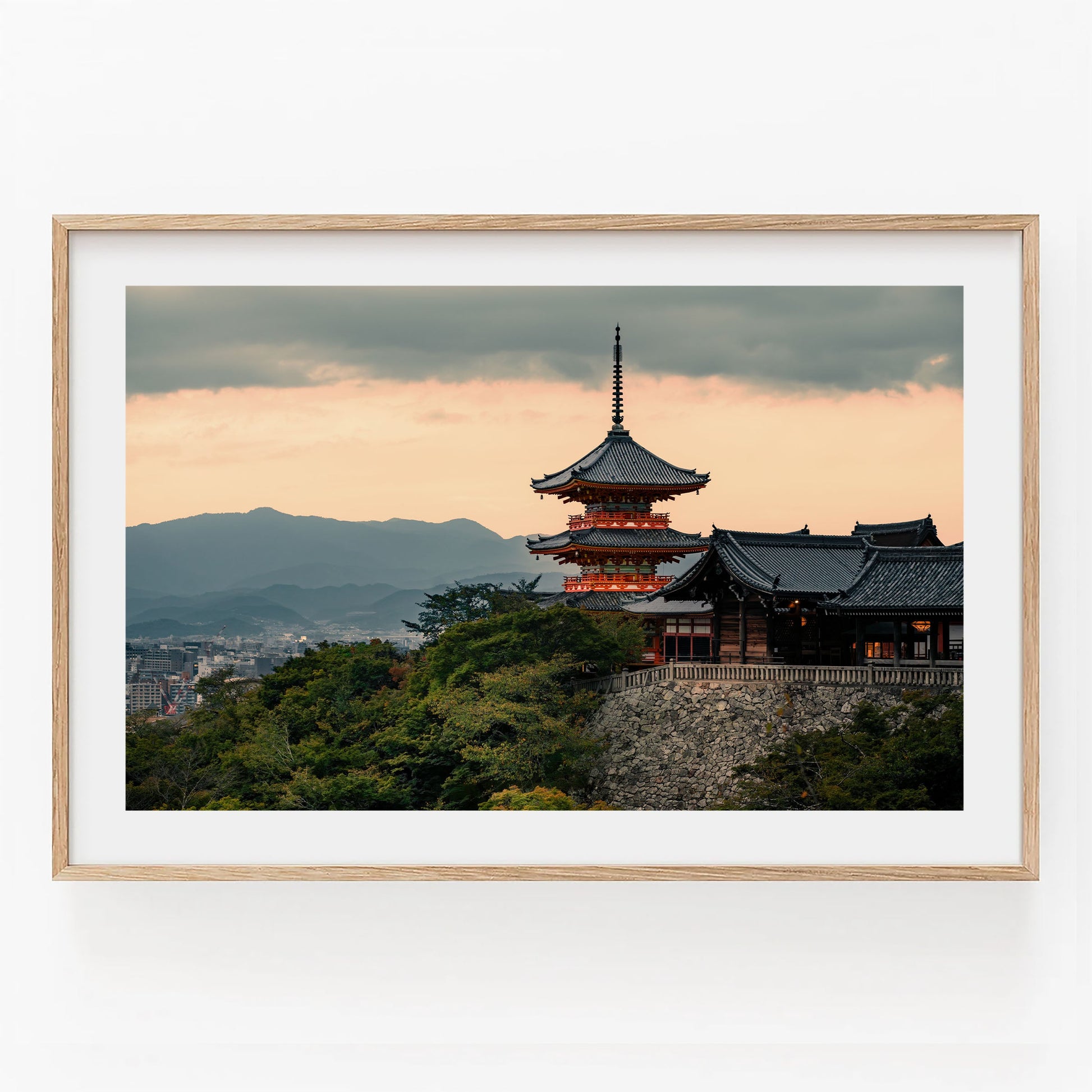 Kiyomizu-dera Sunset II: A light wood-framed Japanese pagoda at sunset with mountains and cityscape in the background.
