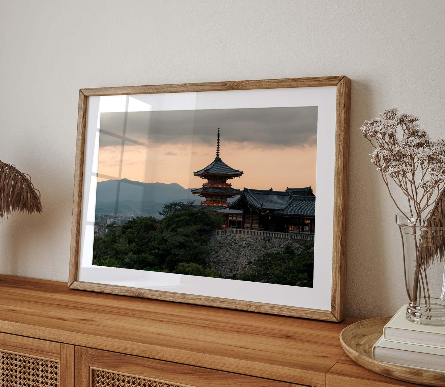 The Kiyomizu-dera Sunset II framed photo, depicting a traditional Japanese temple at sunset, is elegantly displayed on a wooden sideboard with dried flowers.