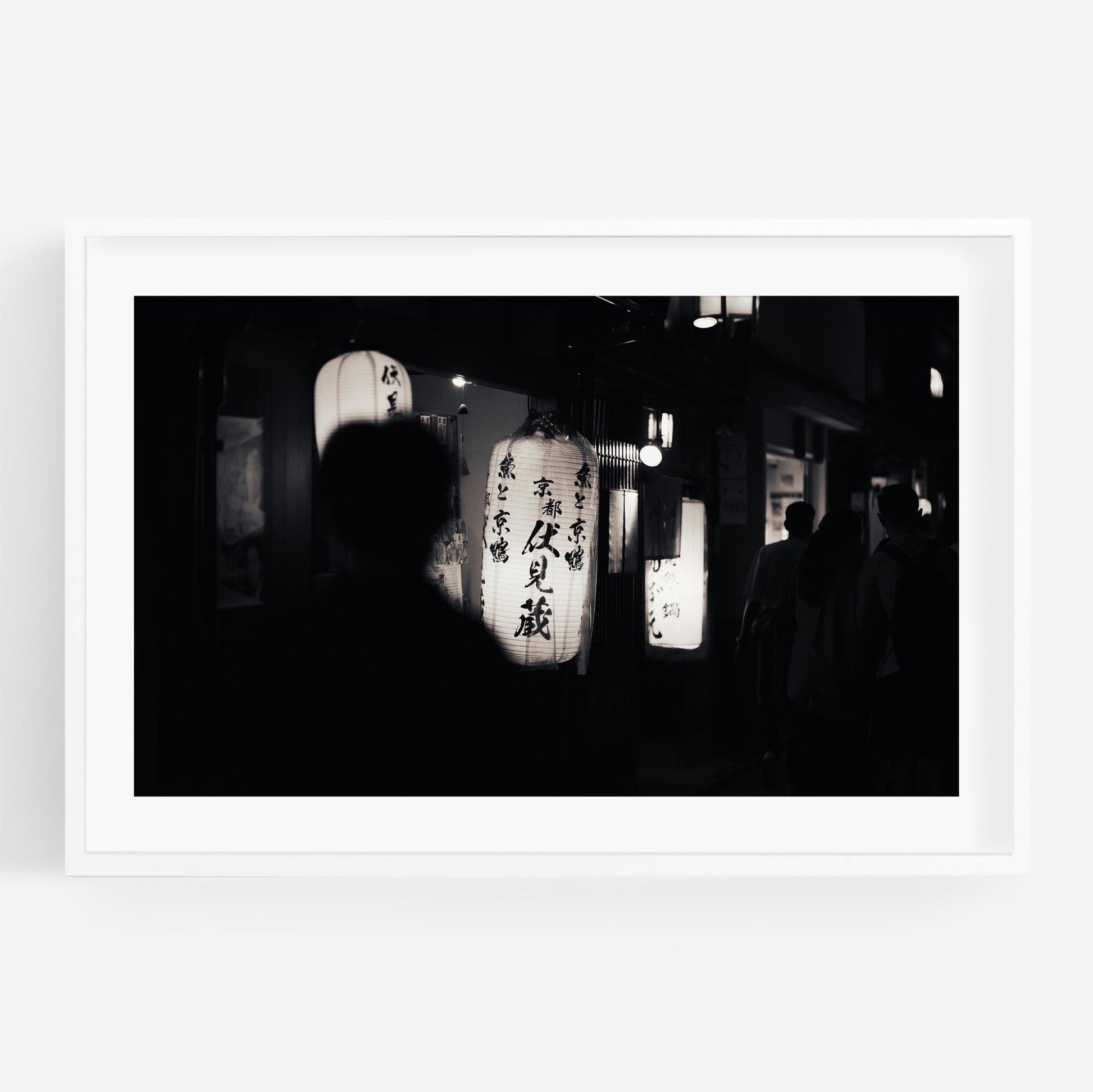 Person silhouetted while walking near illuminated lanterns, captured in the artwork Kyoto At Night - Black and White.