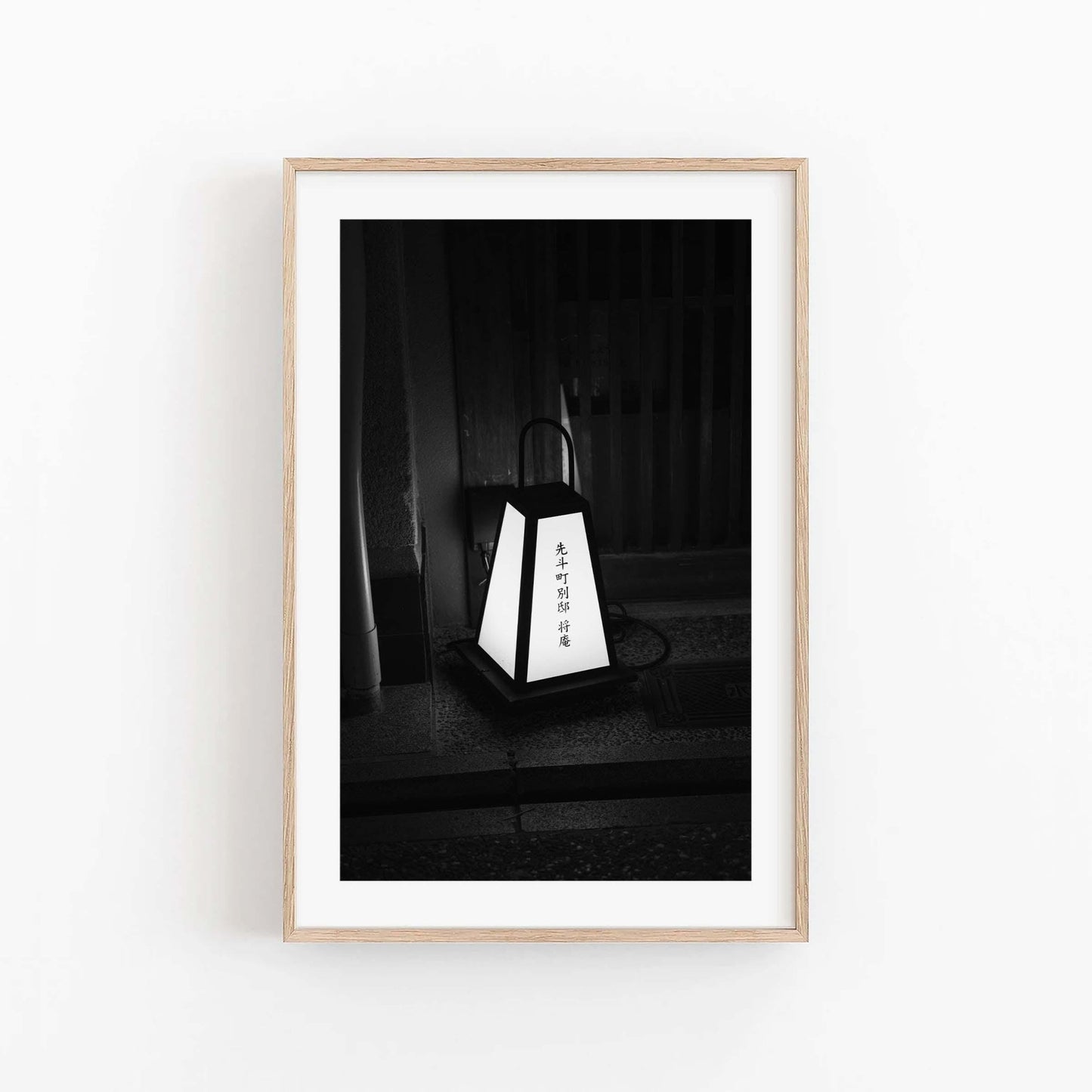 Kyoto Lantern I - Black and White, a photo of a Japanese lantern with calligraphy, framed on a white wall.