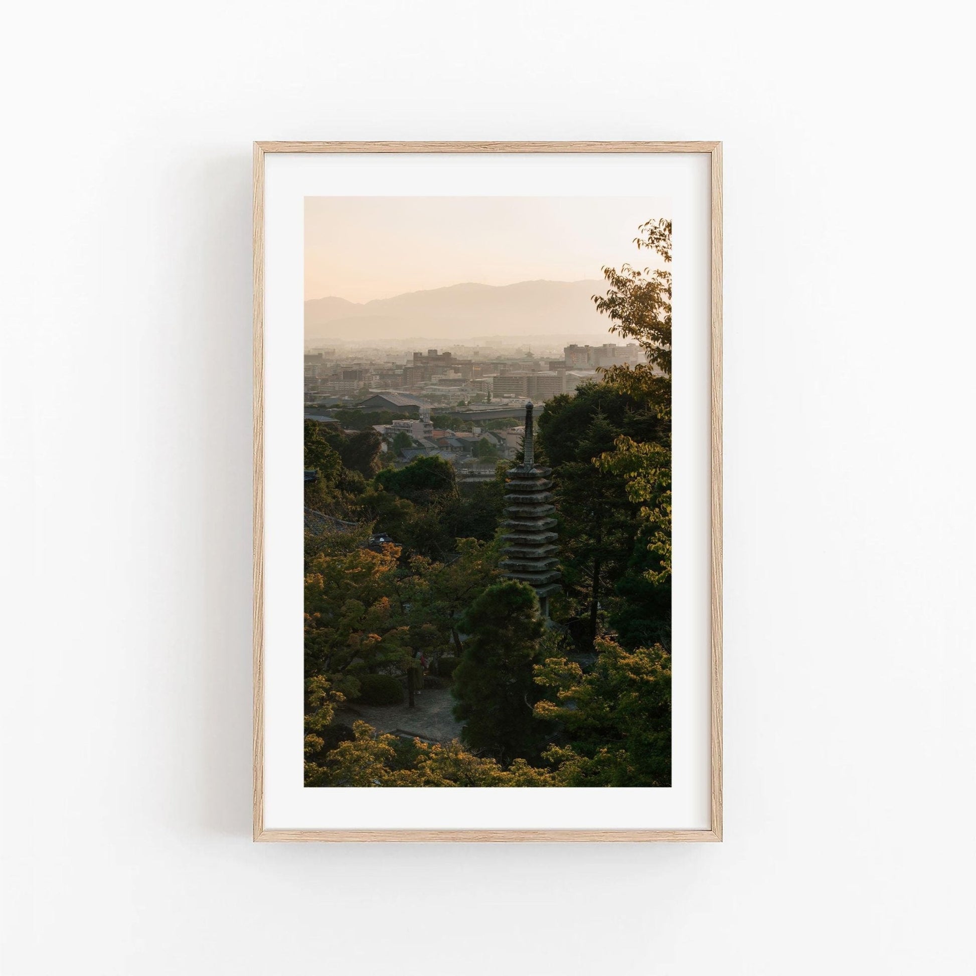 Framed Kyoto Sunset Skyline II photo featuring a cityscape with trees and a pagoda in the distance at sunset.