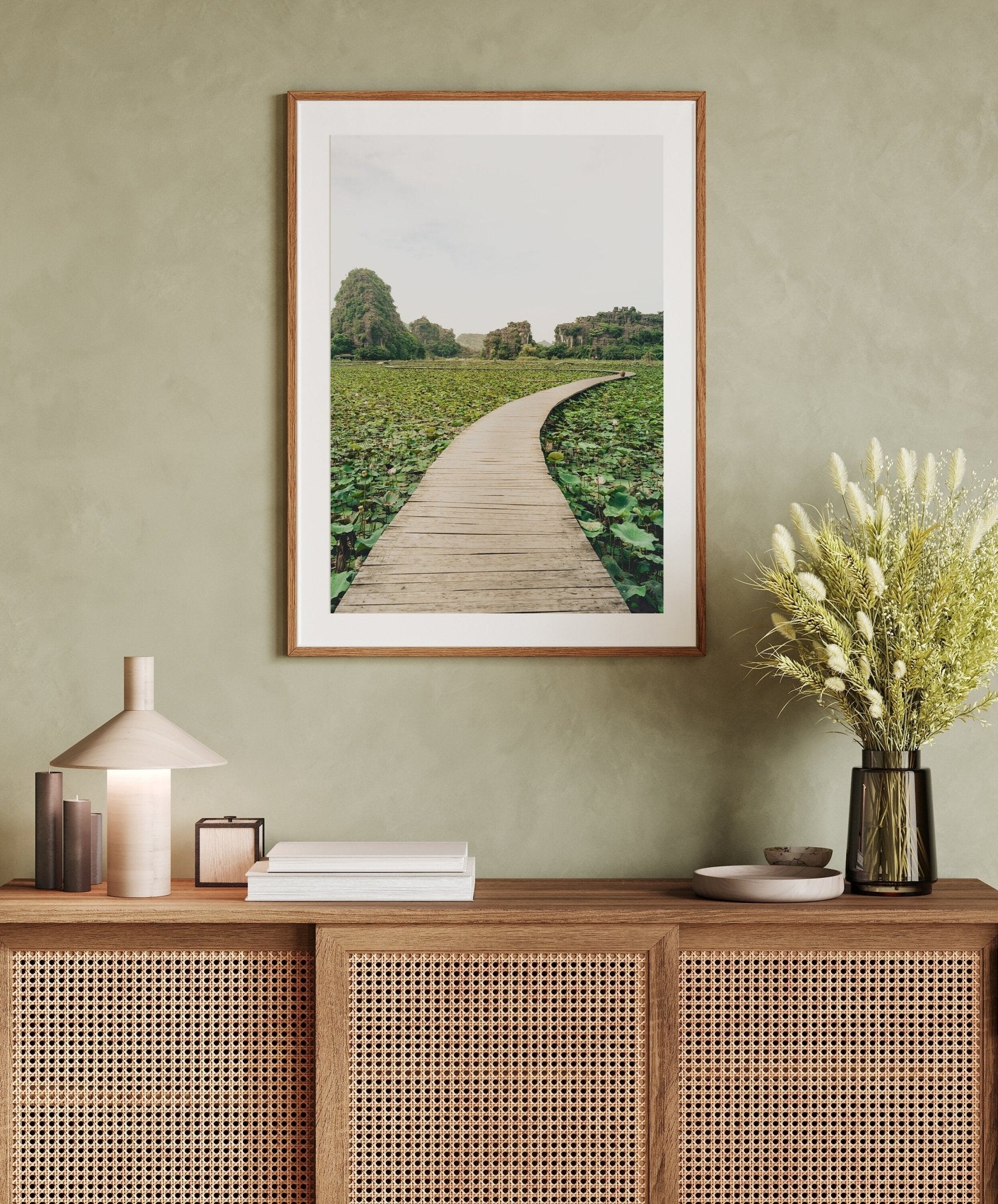 Lead the Way photo above wicker console with vases and books, set against a pale green wall.