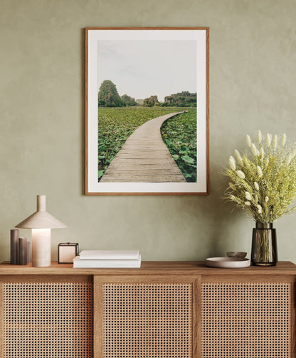 Lead the Way photo above wicker console with vases and books, set against a pale green wall.