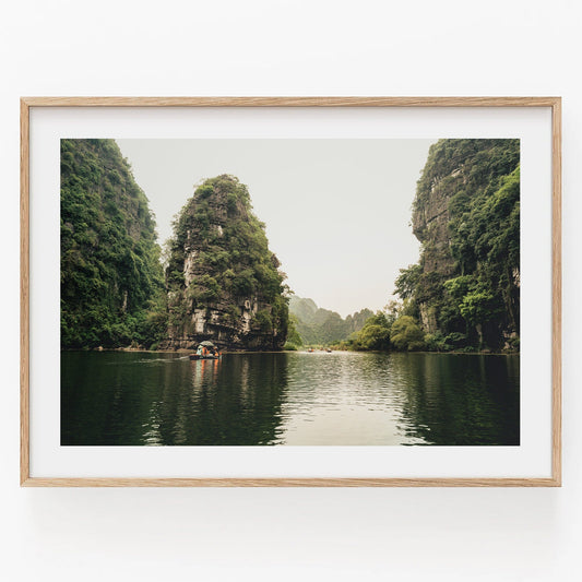 Framed art Limestone Wonders features a tranquil river scene with green cliffs and a small boat.