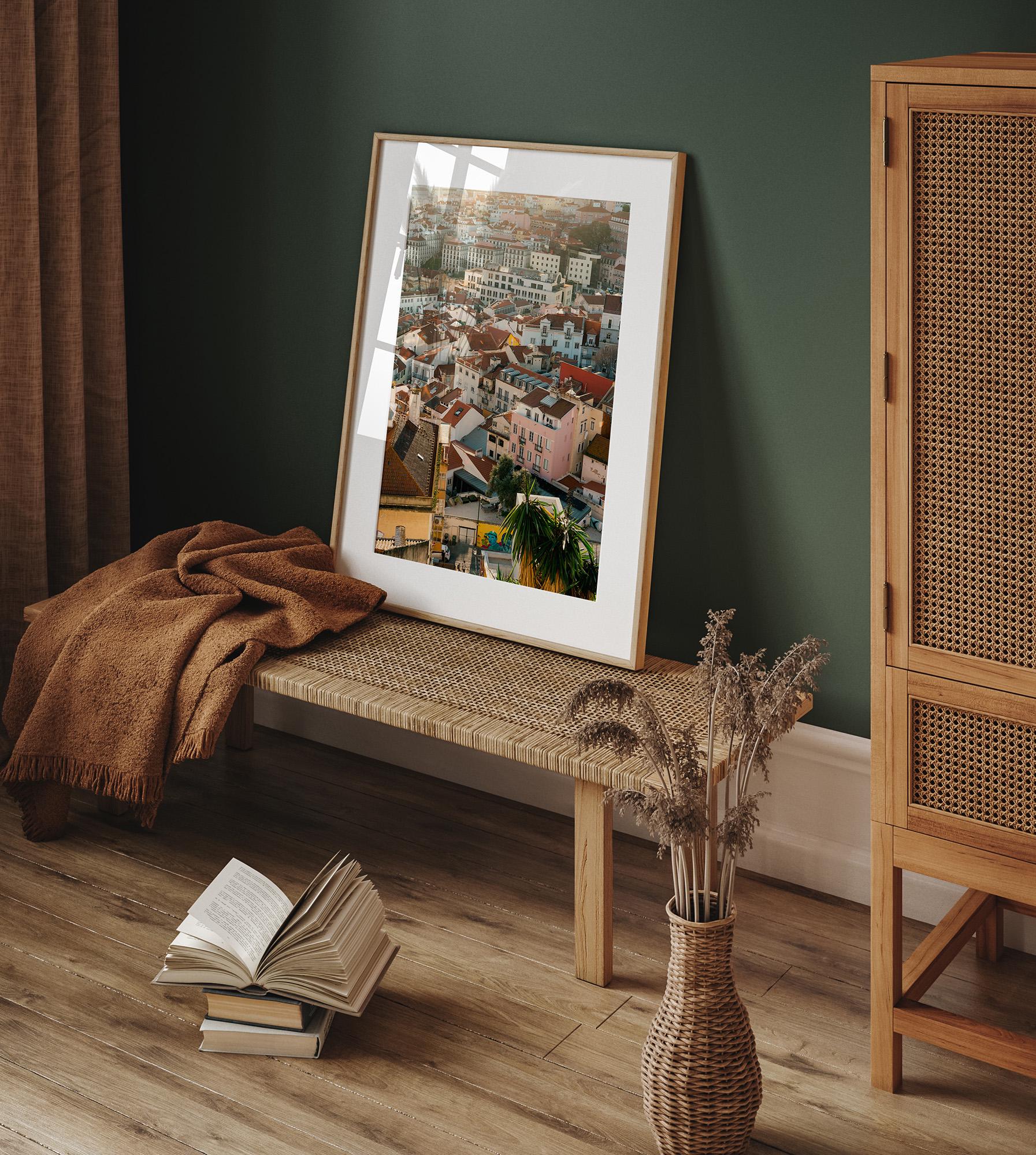 Lisbon Layers framed cityscape on woven bench with brown blanket, book, and dried flowers on wood floor.
