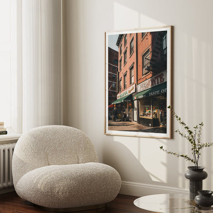 Cozy room with a soft white chair, Little Italy photo on the wall, and a small table with a vase.