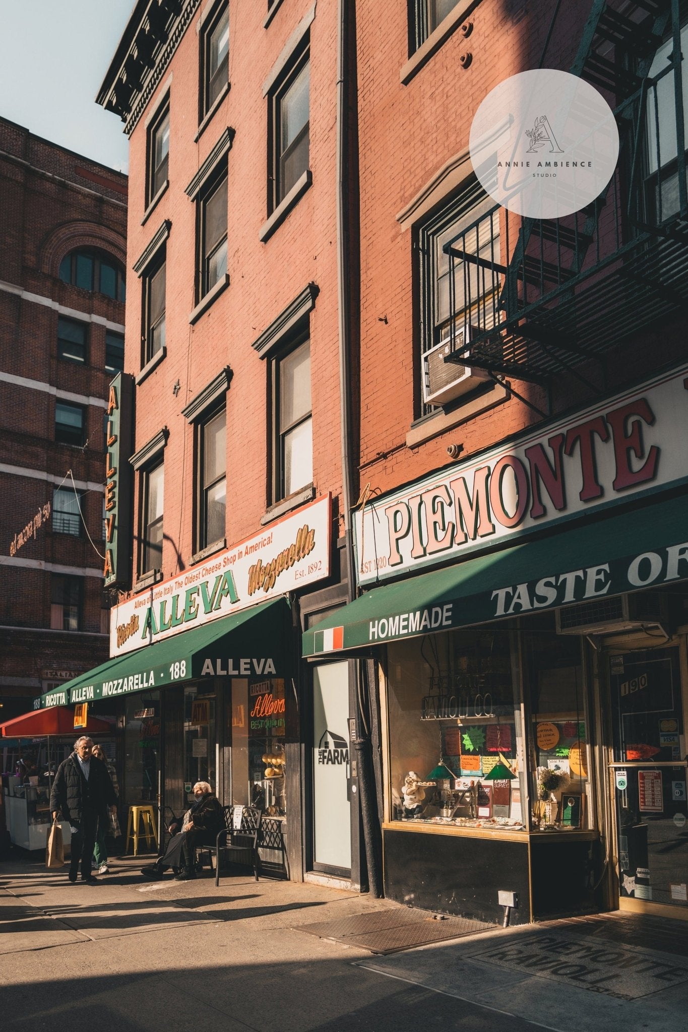 Little Italy: A historic deli and cheese shop with brick buildings and passersby on a charming street.