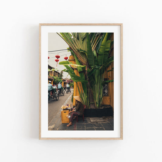 Local Vendor: A framed photo of a person in a conical hat near lush plants and a yellow wall.