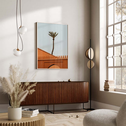 A modern living room featuring a Marrakesh Palm Tree, pendant lights, a large window, and framed artwork on the wall.