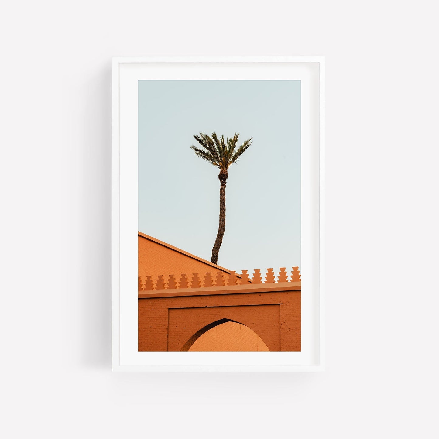 Framed image titled Marrakesh Palm Tree: An orange building with a palm tree against a pale sky.