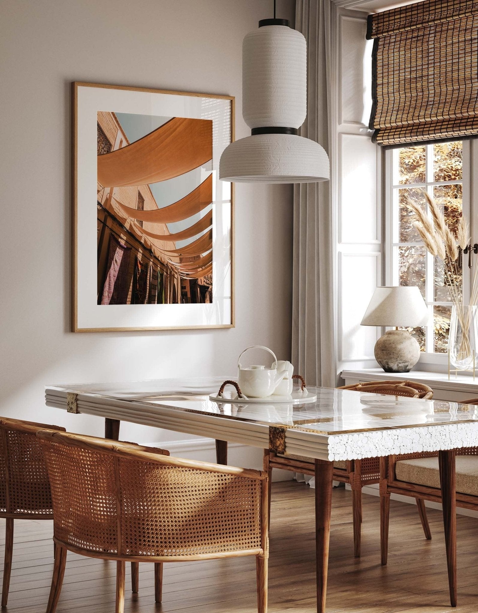 Stylish dining area with wicker chairs, a marble table, and a large framed photo titled Marrakesh Souk II on the wall.