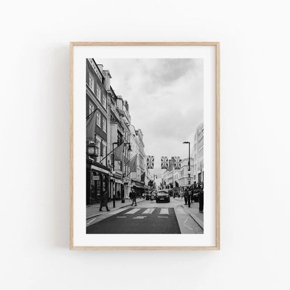 Mayfair Black and White features a city street photo with people, buildings, flags, in a light wooden frame.