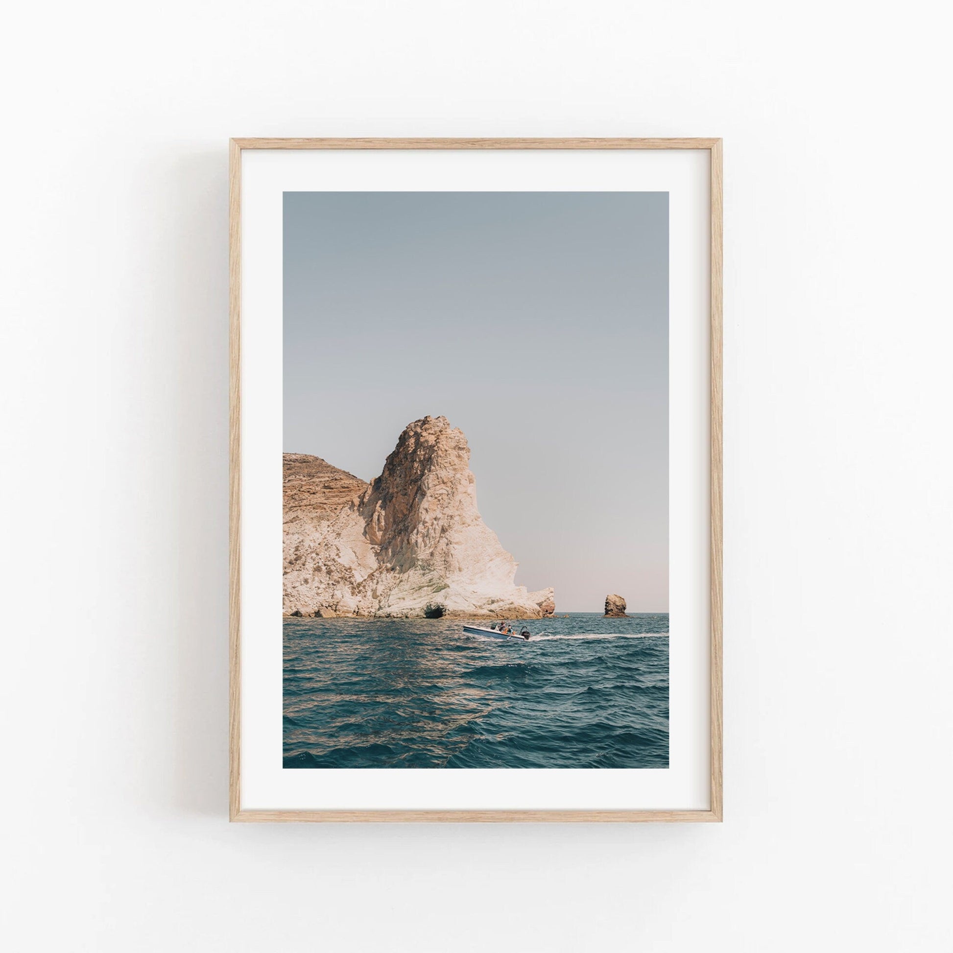 Framed Mediterranean Adventure photo of a rocky sea cliff with a boat under clear skies.