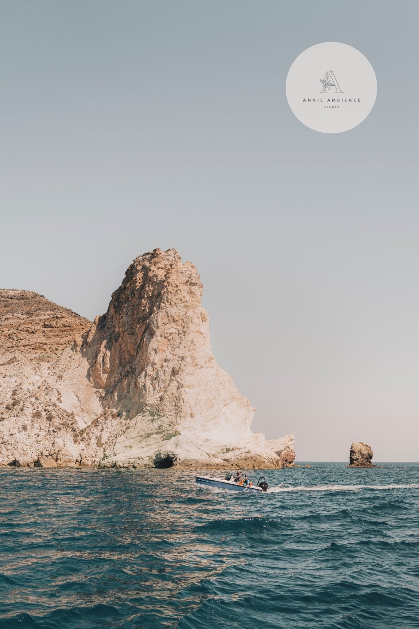 Boat on blue sea near a rocky cliff under clear sky, featuring Mediterranean Adventure logo in top right corner.