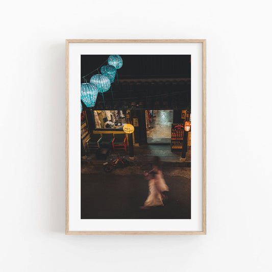 Framed Midnight Memories photo of a street scene with blurred motion of a woman and hanging lanterns.