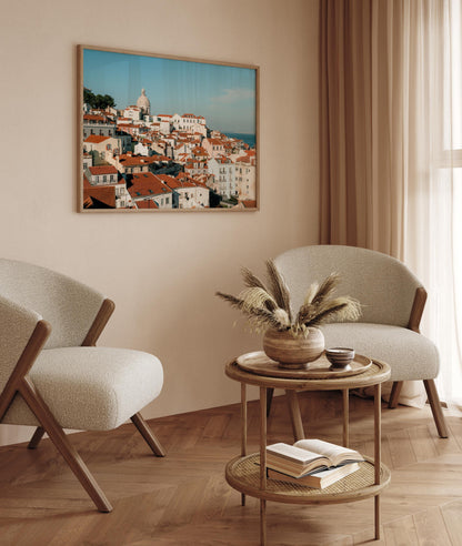 Cozy living room with two chairs, round table, Miradouro artwork, pampas grass vase, and open book.