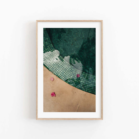 Framed photo of the Moroccan Pool shows pink petals on water with beige stone and a tiled pool edge.