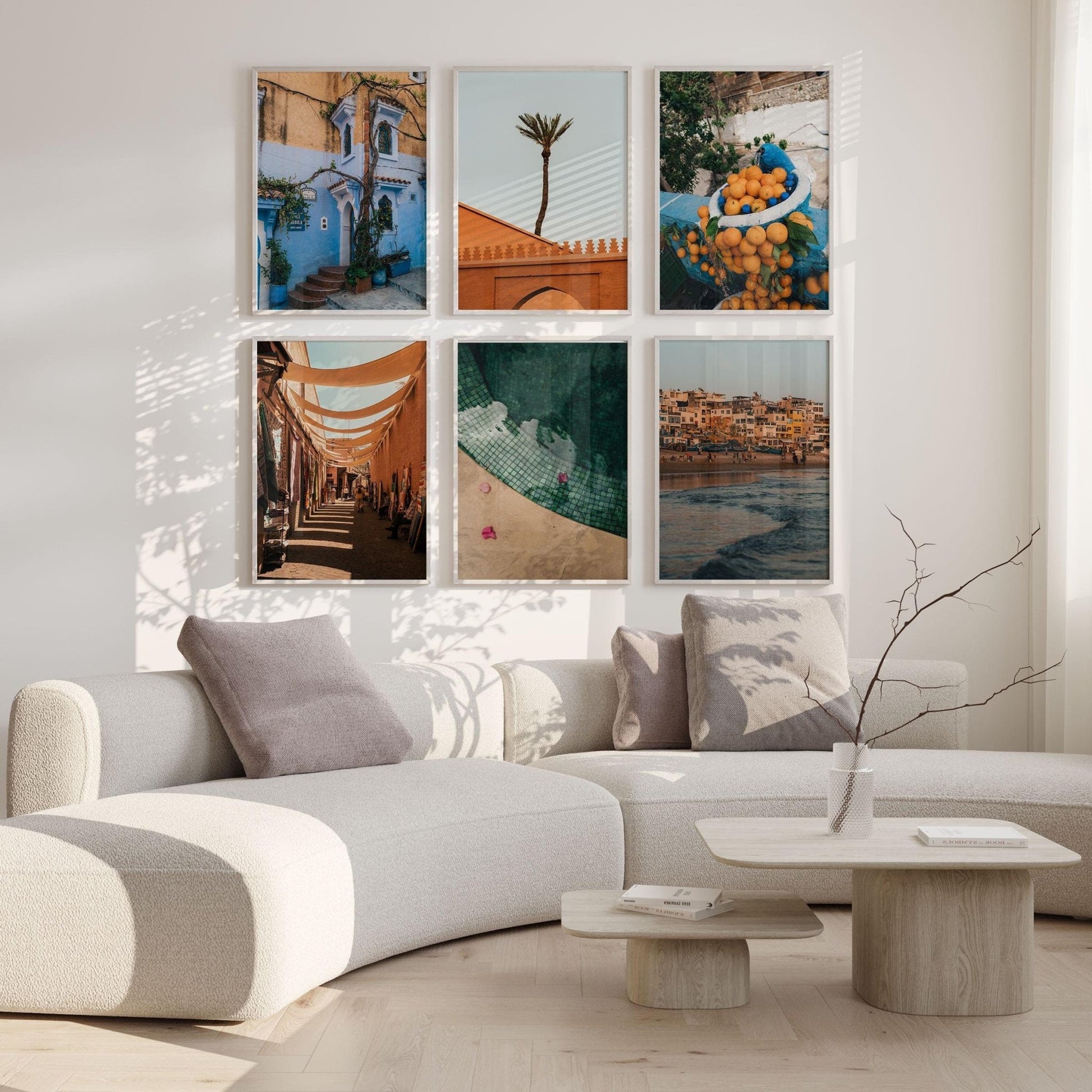 Minimalist living room with a curved sofa, light wood tables, and the Morocco - Set of 6 travel photos on the wall.