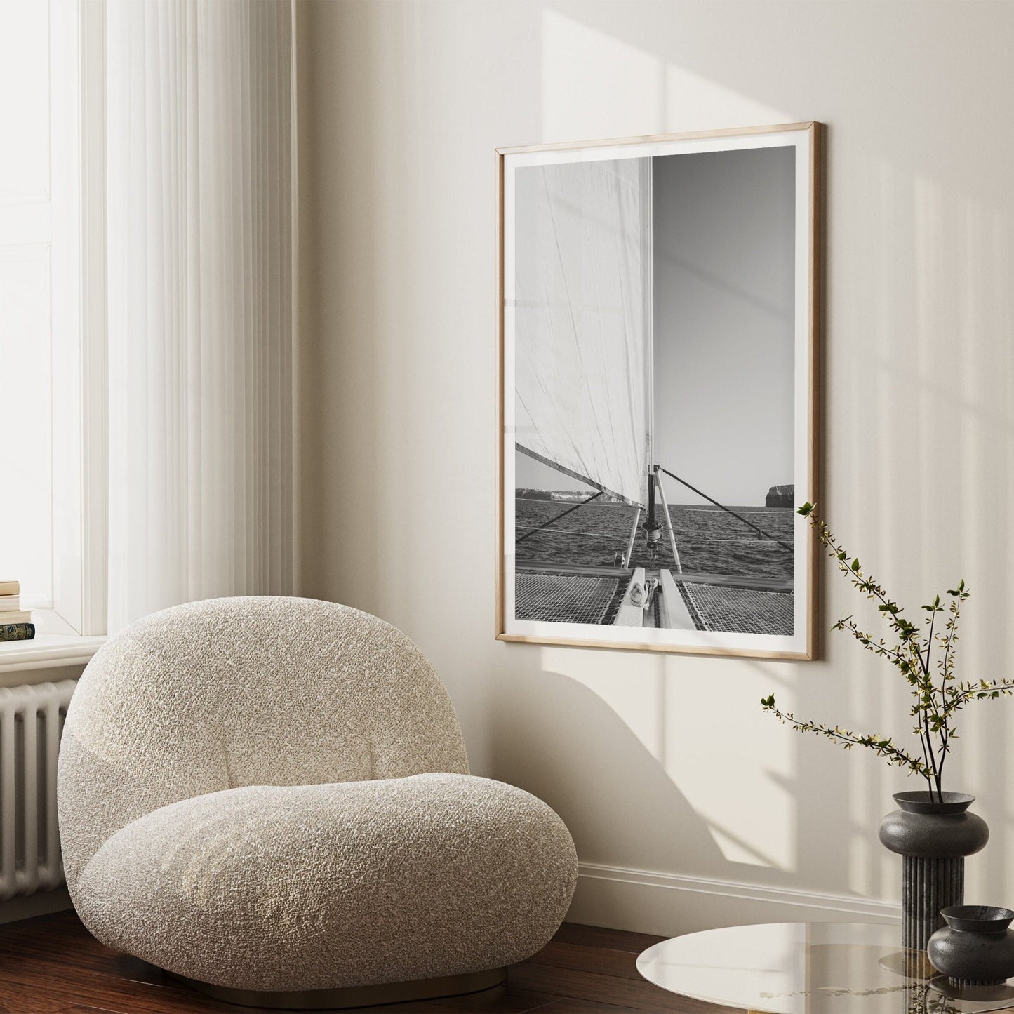 A minimalist space with a plush chair, Nautical Harmony photo, and a table with a branch-filled vase.