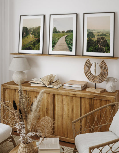 A cozy room featuring a Ninh Binh set of 3 wooden sideboards, framed photos, books, a lamp, dried flowers, and decor.