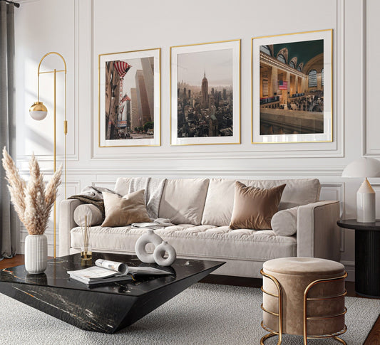 A modern living room with a beige sofa, abstract decor, and NYC Midtown - Set of 3 framed cityscape photos on the wall.