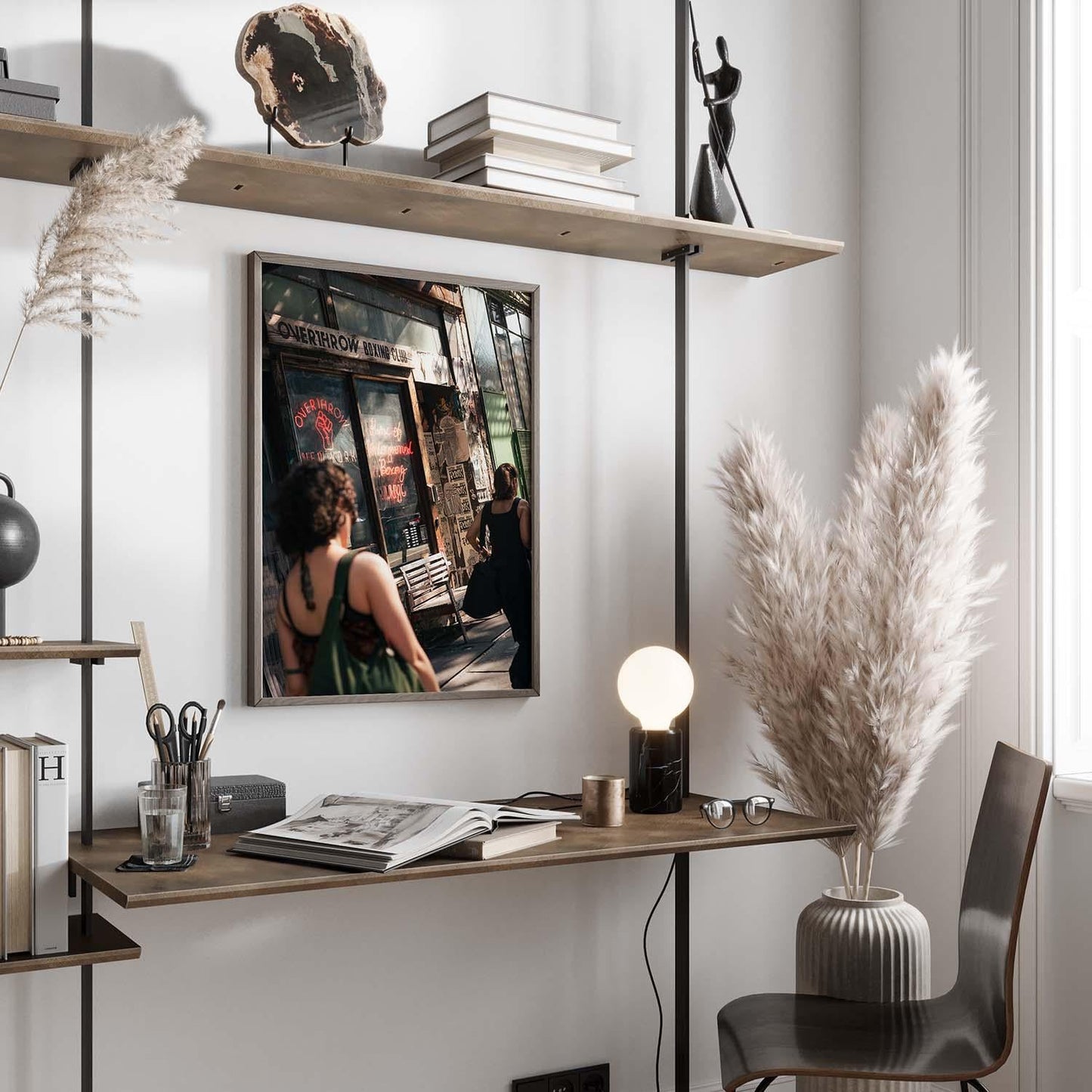 Minimalist workspace with Overthrow Boxing Club decor: wooden shelves, pampas grass, framed photo, globe, and lamp on desk.