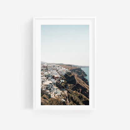 Perched framed photo of white buildings on a cliffside above the sea under a clear sky.