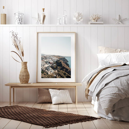 Bedroom with coastal decor featuring a framed Perched seaside photo, wicker vase, and neutral-toned bedding.