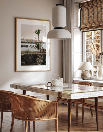 Playa Jardín dining room with marble table, woven chairs, big window, and framed coastal wall art.