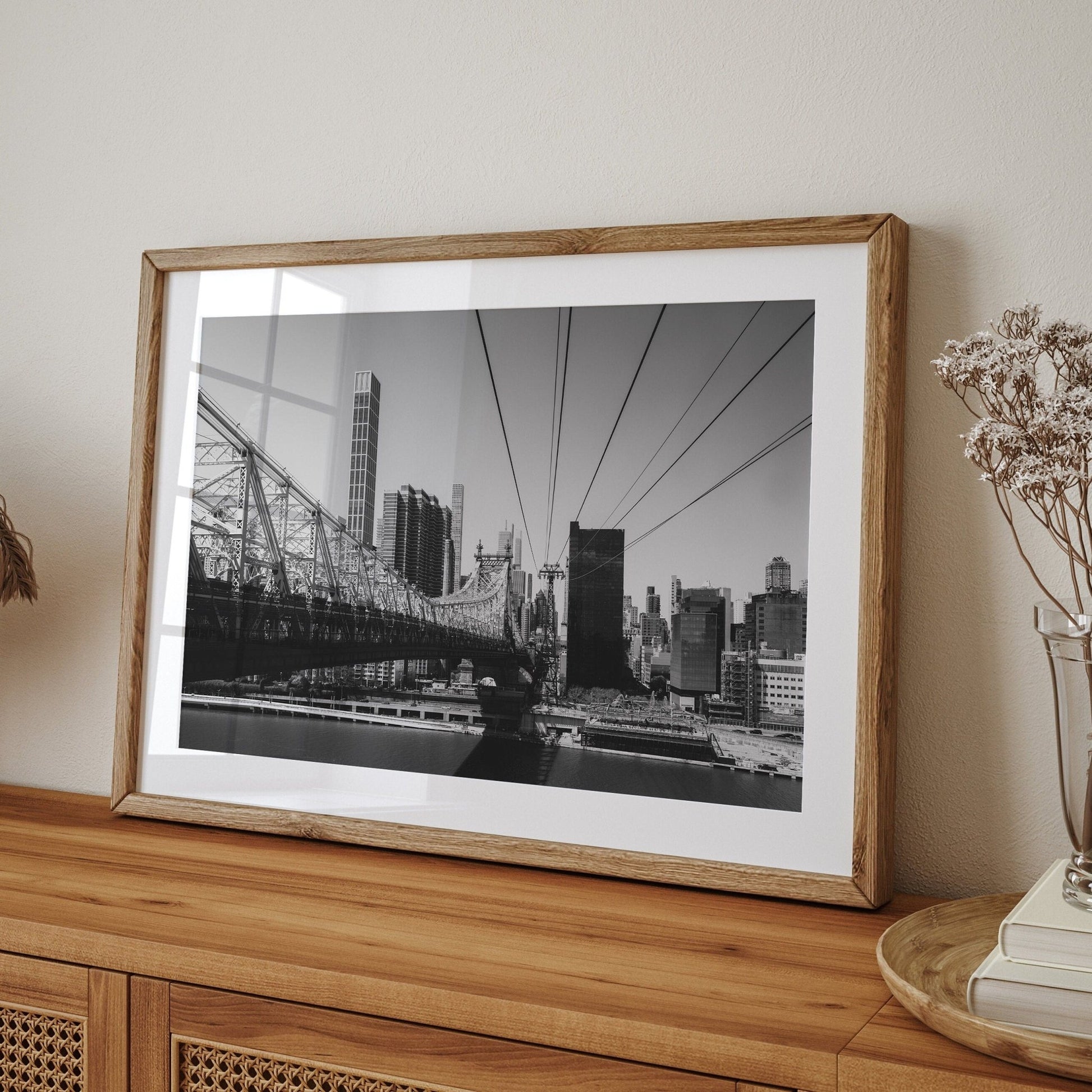 Queensboro Bridge Black and White photo on a wooden sideboard with dried flowers in a vase.