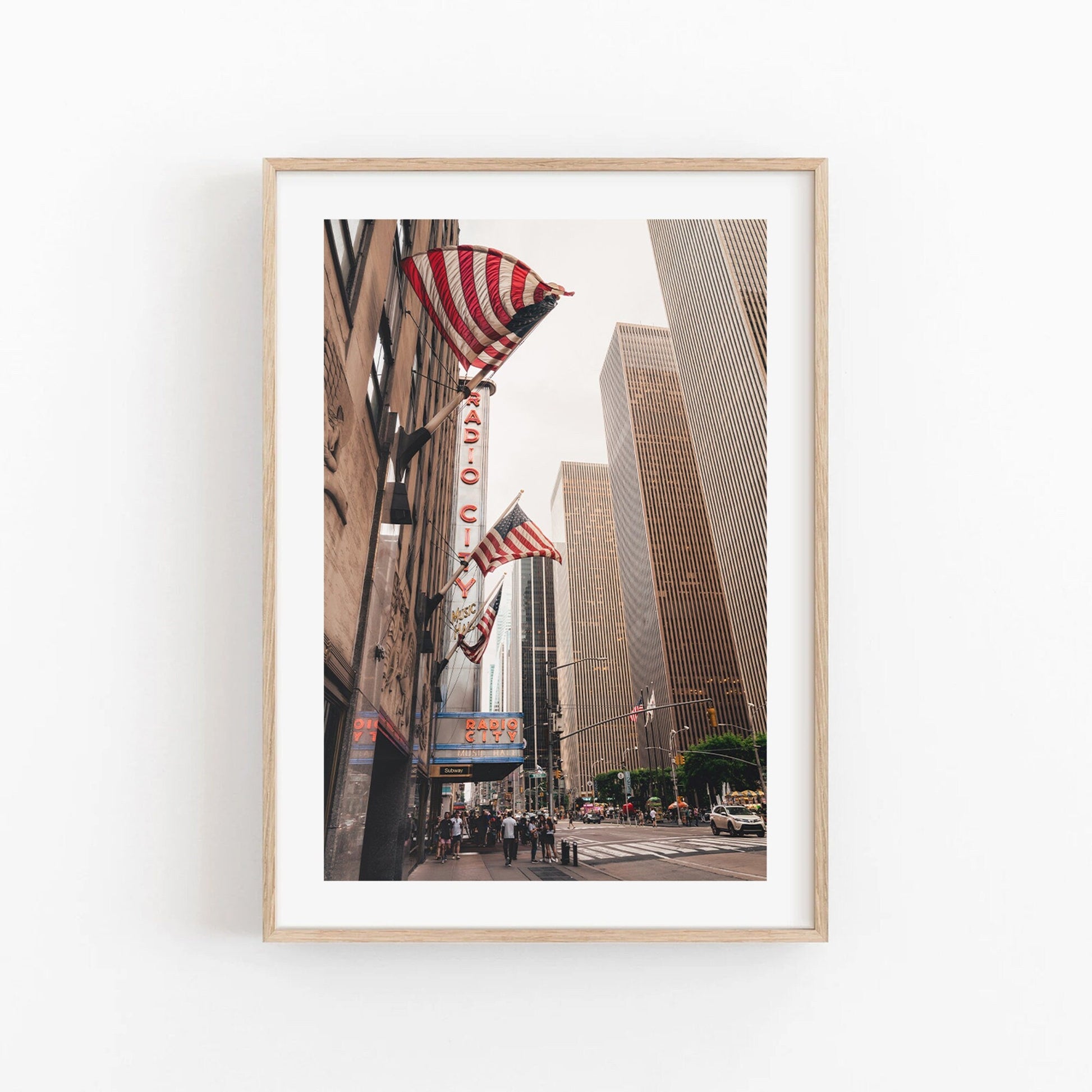 Framed photo of Radio City Music Hall with tall buildings and American flags.