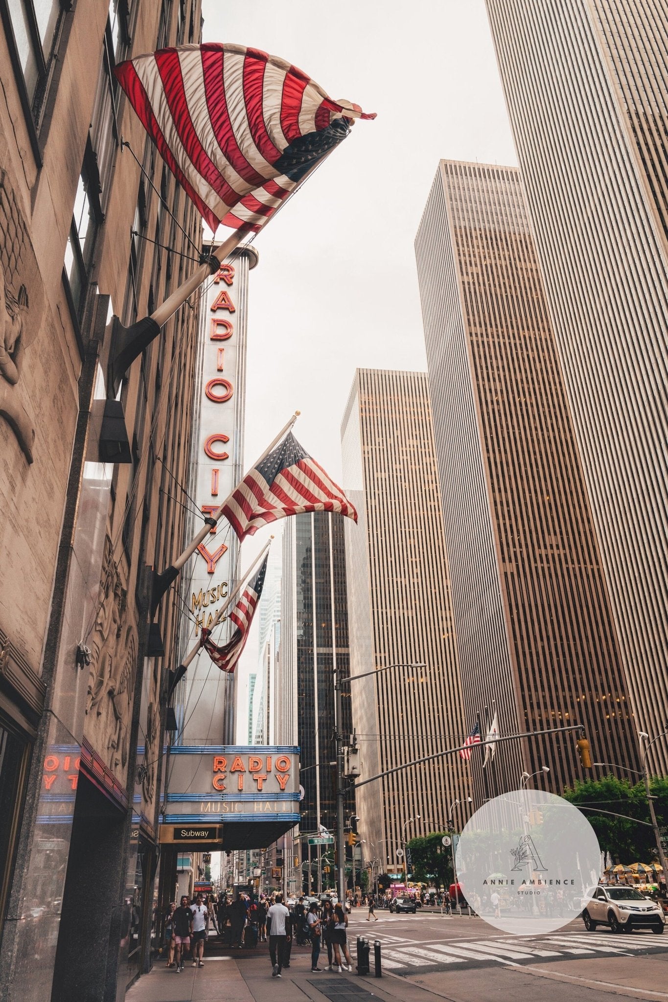 Street view of Radio City Music Hall with flags and skyscrapers in NYC.