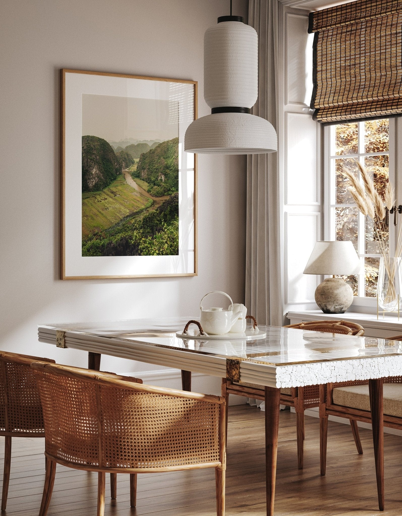 Stylish dining area: marble table, wicker chairs, teapot set, and the River Valley photography print near a large window.