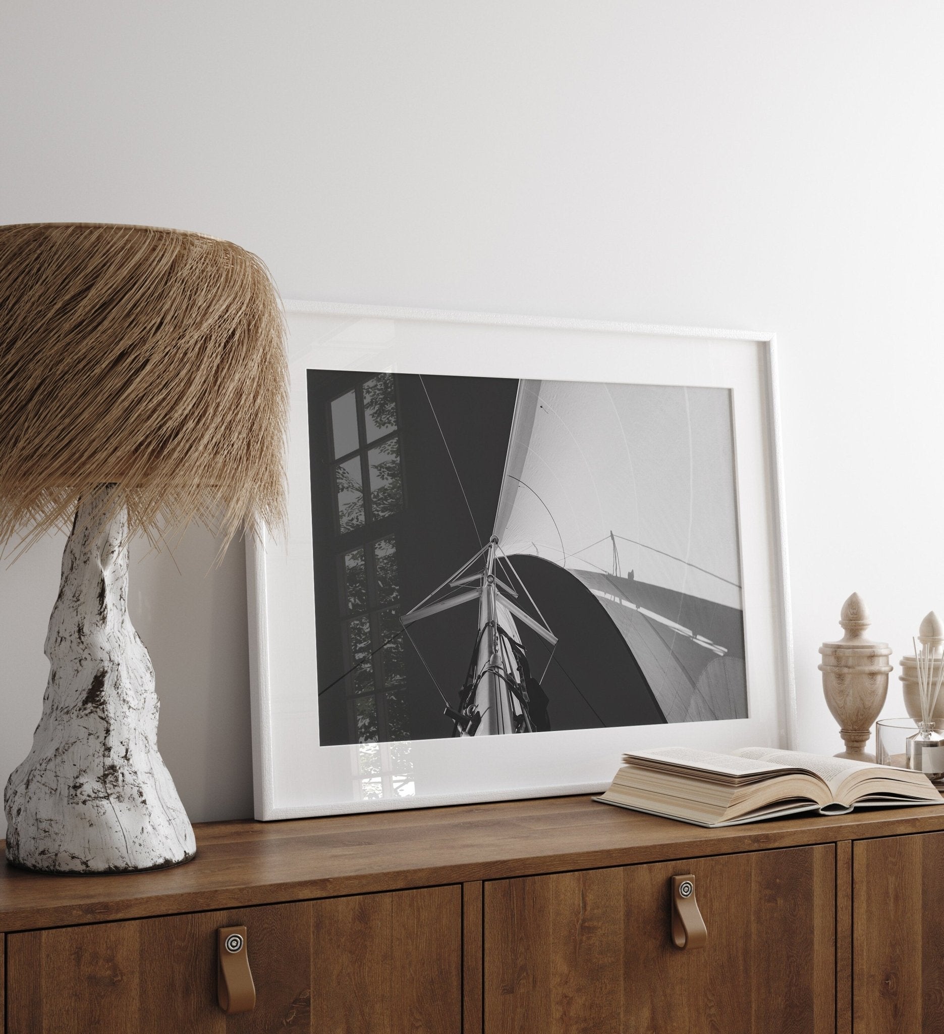 Sailing Bliss Black and White photo on a wooden sideboard with a lamp and open book in minimalist room.