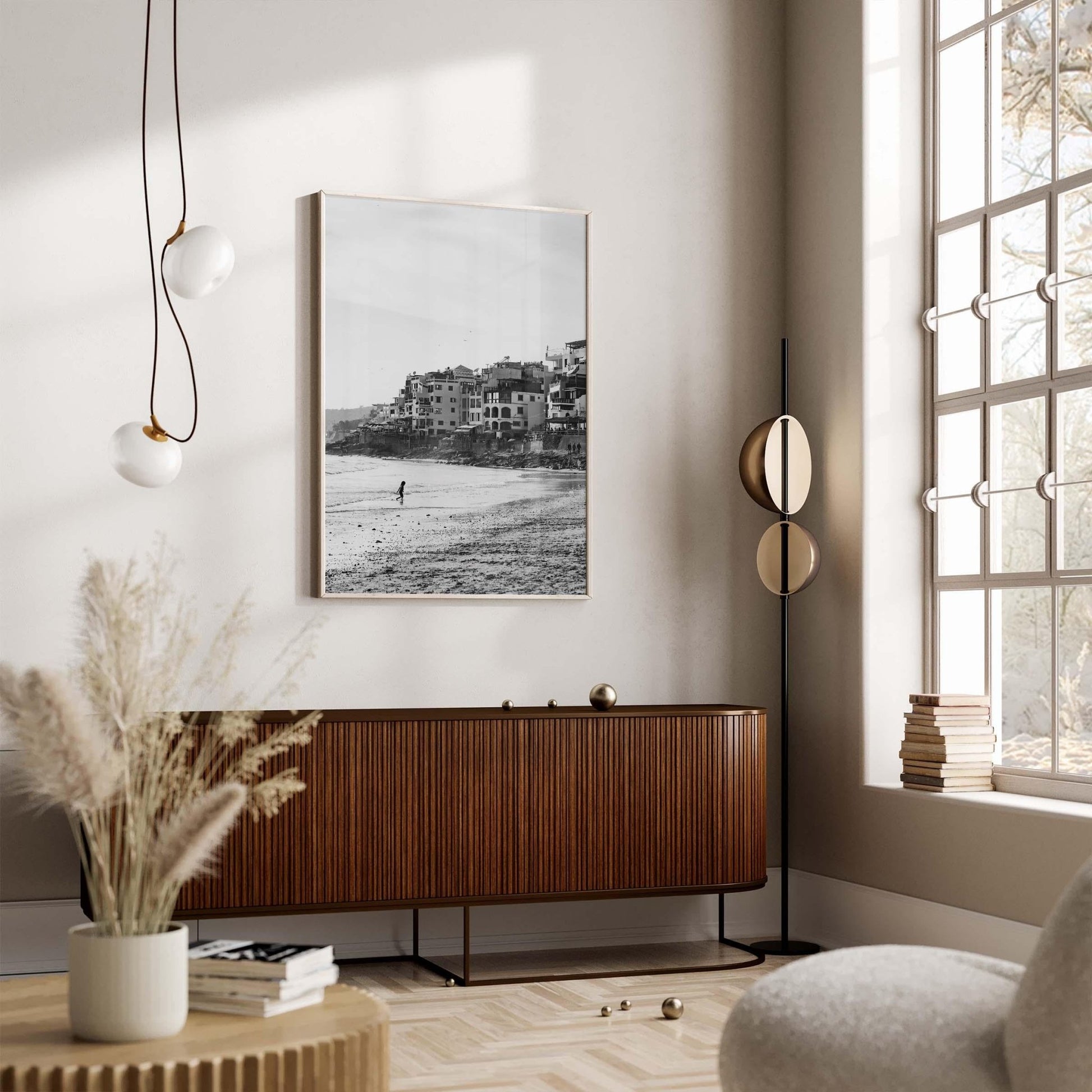 A stylish living room with a wooden sideboard, the Sandy Toes Black and White photo, modern pendant lighting, and a large view window.