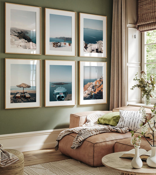 A cozy room with a sofa and Santorini - Set of 6 coastal landscapes on a green wall, by a window with natural light.