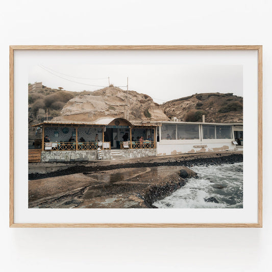 Seaside Dining: A stone patio and wooden accents cafe set against a rocky hillside with crashing waves.