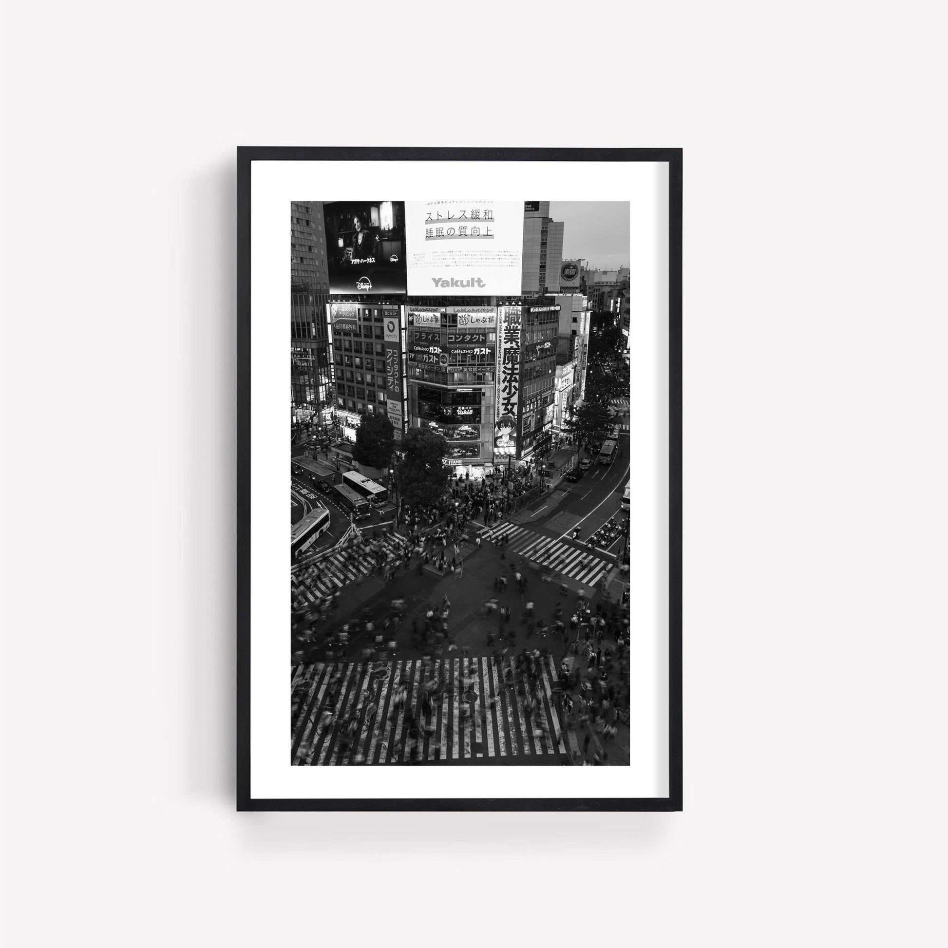 Shibuya Crossing - Black and White features a bustling city intersection with neon signs and crossing pedestrians.