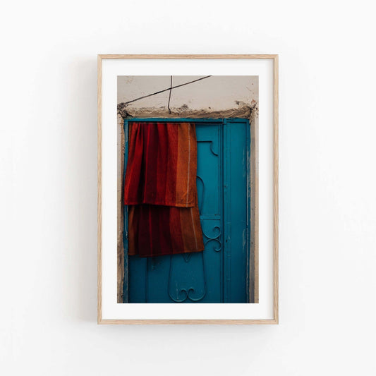 A framed photo titled Taghazout Door shows a blue door draped with red-orange fabric.