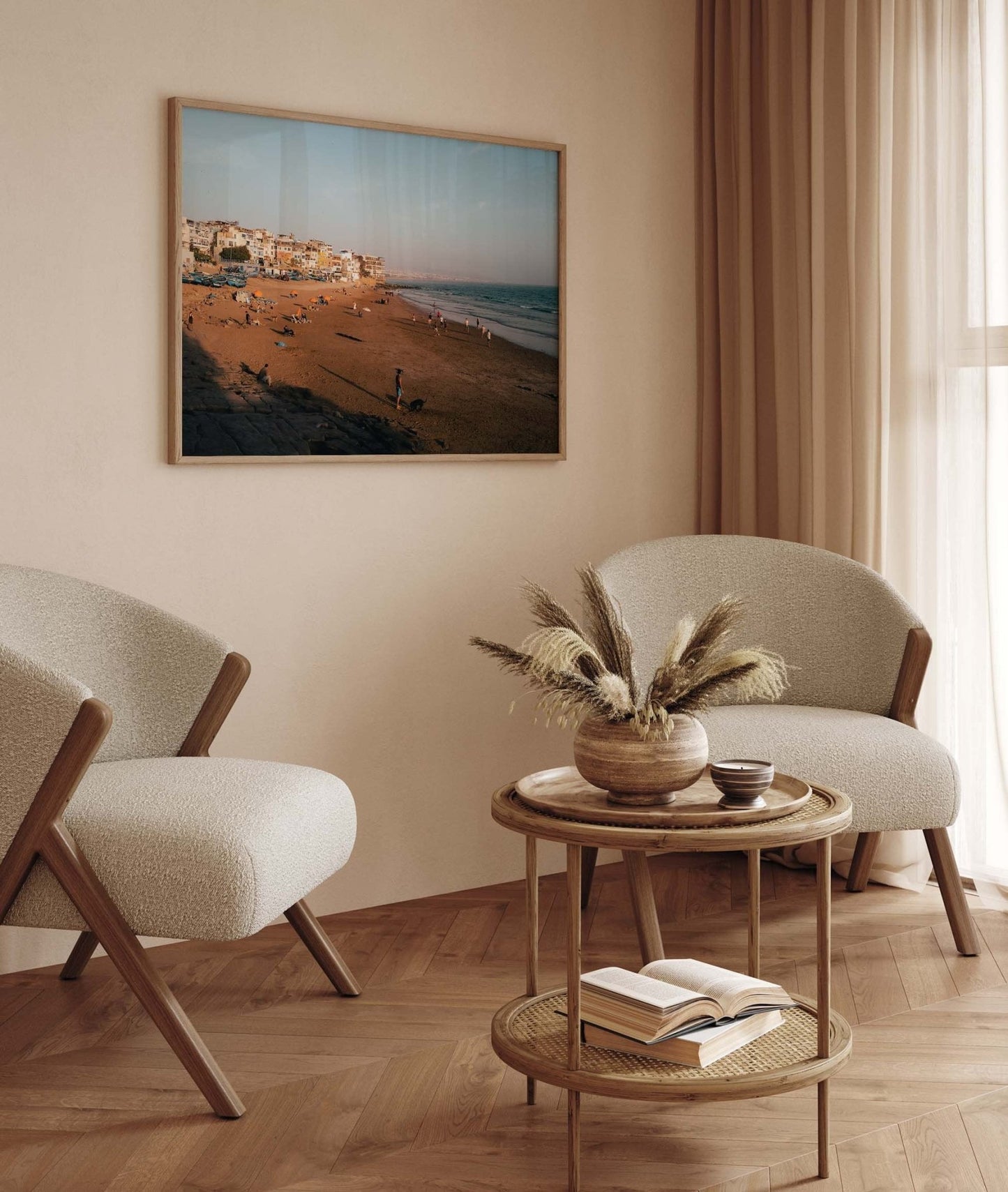 Cozy room with two chairs, a round table holding a vase of dried plants and an open book, plus Taghazout I beach photo on wall.