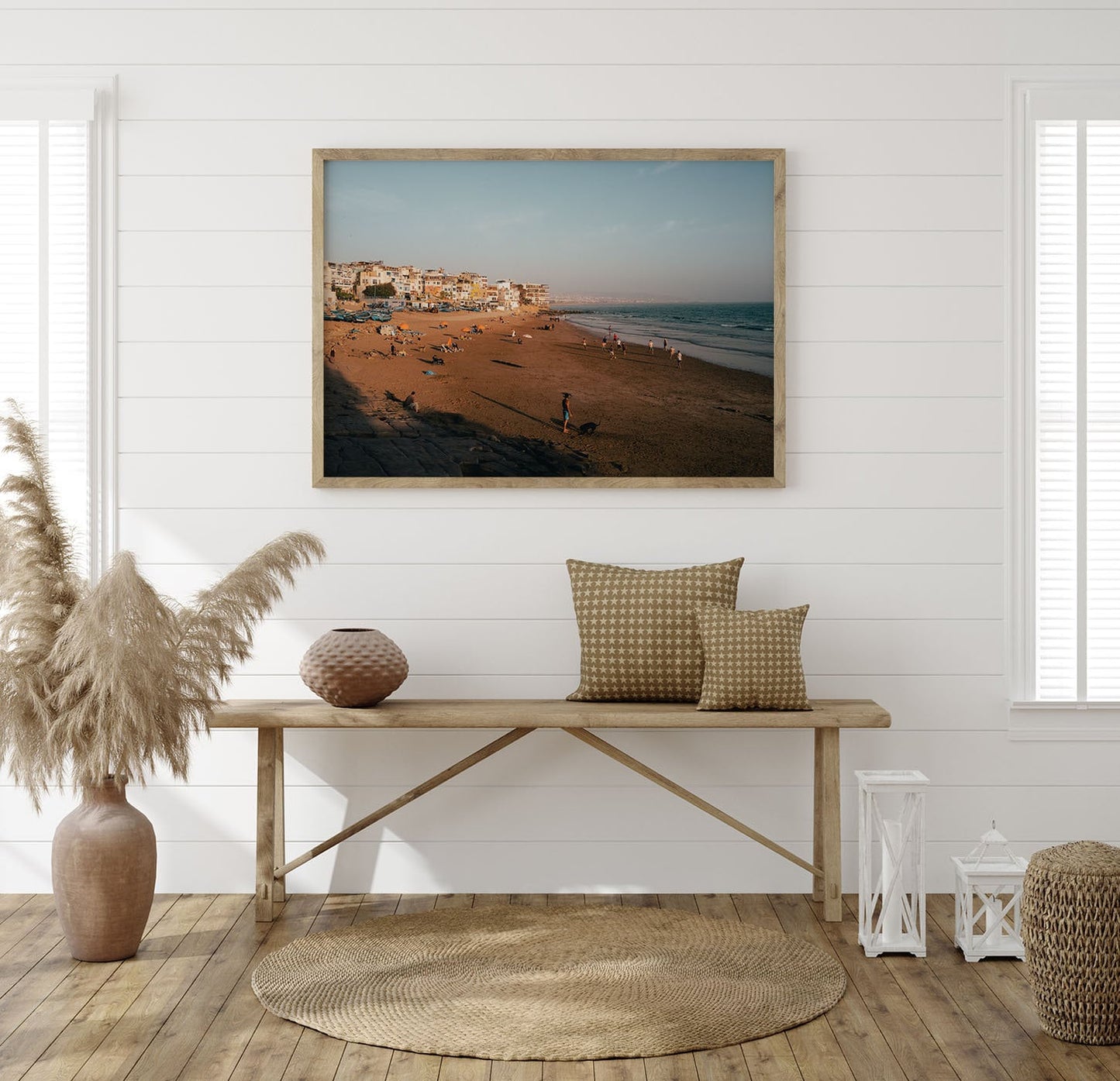 Taghazout I framed on a white wall above a wooden bench with pillows and vases in a sunlit room.