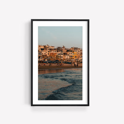 A framed photo titled Taghazout Wave, showcasing a sunset beach scene with waves and buildings in the background.