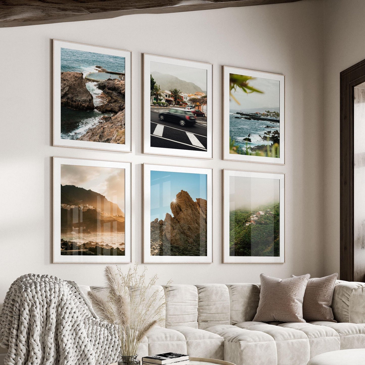 Six "Tenerife - Set of 6" framed photos hang above a beige sofa with pillows and a knit blanket.